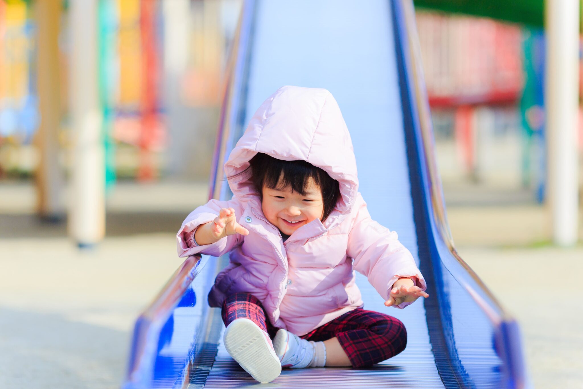 すべり台であそび、笑顔を見せる子ども
